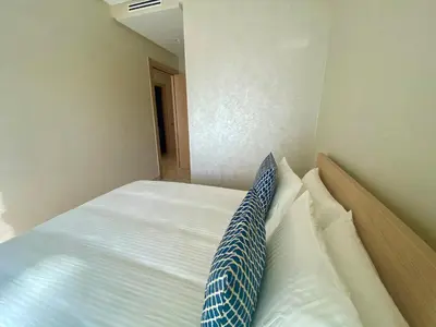 a bed with a blue and white pillow on it at Luxueux Appartement avec Vue Panoramique, Proche de la Gare WELCOME STAY in Casablanca