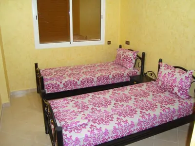 a bedroom with a bed with pink sheets and a window at Yasmine Appartements in Temara