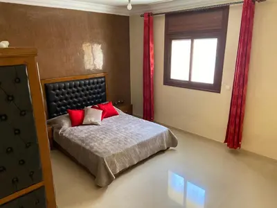 a bedroom with a bed with red pillows and a window at Apparemment à mohammadia in Mohammedia