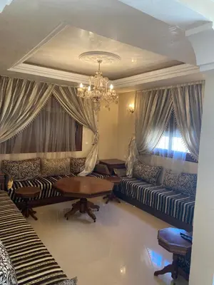 a living room with couches and a table and a chandelier at Apparemment à mohammadia in Mohammedia