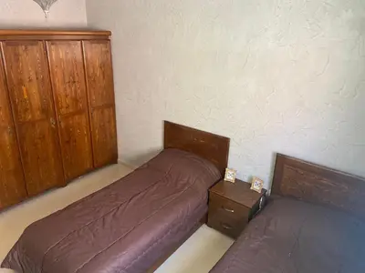 a bedroom with two beds and wooden cabinets at Apparemment à mohammadia in Mohammedia