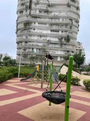 a playground in front of a tall building at Magnifique appartement Casa Finance City in Casablanca