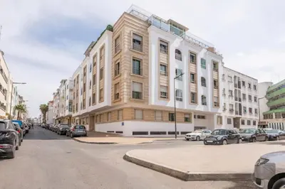 a large building on a city street with parked cars at Layover Guest House Apartment & parking Rabat Agdal City Center in Rabat