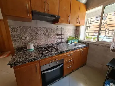 a kitchen with wooden cabinets and a stove top oven at Chez Najib et Ziad in Temara