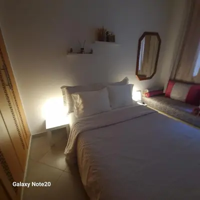 a bedroom with a white bed and a couch at Chez Najib et Ziad in Temara