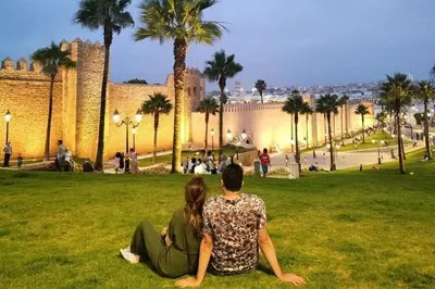 two people sitting on the grass in a park at Appartement de standing vue sur mer à Mohammedia in Mohammedia