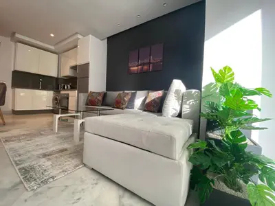 a living room with a white couch and a kitchen at CORNICHE CASABLANCA - SUBLIME F2 NEUF in Casablanca