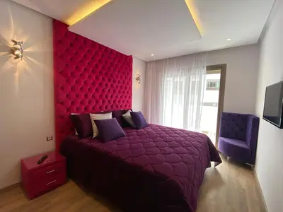 a bedroom with a red bed with a red headboard at CORNICHE CASABLANCA - VINTAGE F2 NEUF in Casablanca