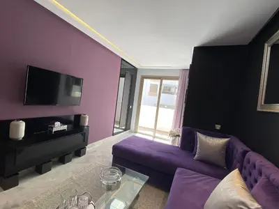 a living room with a purple couch and a tv at CORNICHE CASABLANCA - VINTAGE F2 NEUF in Casablanca