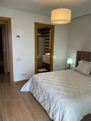 a bedroom with a large white bed and a lamp at Superb Apartment on 14th floor with Jacuzzi in Casablanca