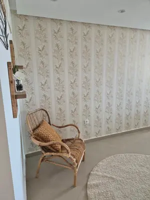 a wicker chair sitting in a room with wallpaper at My Cosy Place Rabat - Cosy Home Wifak Temara in Temara