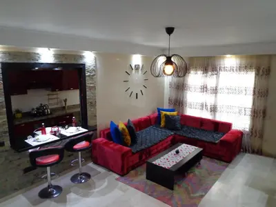 a living room with a red couch and a clock on the wall at Zen Home in Casablanca