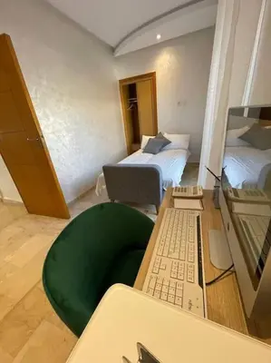 a room with two beds and a desk with a laptop at A 2 minutes de Casa Finance City, appartement avec 2 Chambres in Casablanca