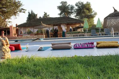 a row of pillows sitting on the ground next to a pool at Ferme Sacrée Nature in O Ben Slimane