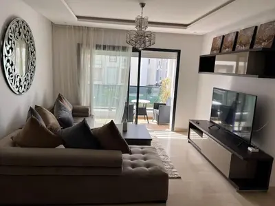 a living room with a couch and a flat screen tv at Superbe appartement avec piscine in Rabat