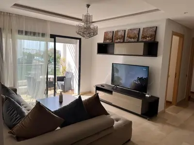 a living room with a couch and a flat screen tv at Superbe appartement avec piscine in Rabat