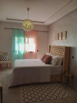 a bedroom with a large bed and a chandelier at Superbe Appartement Bouskoura in Bouskoura