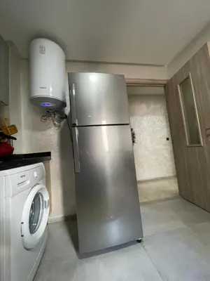 a stainless steel refrigerator in a kitchen with a washing machine at Superbe Appartement Bouskoura in Bouskoura