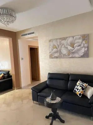a living room with a black couch and a flower painting at Big luxury apartment near airport in Nouaceur