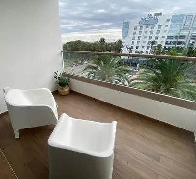 a balcony with a white chair and a view of a building at Luxueux appartement avec vue panoramique WELCOME STAY in Mohammedia