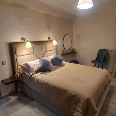a bedroom with a large bed and a blue chair at Miramare Cosy appartement pied dans l'eau avec piscine in Mohammedia