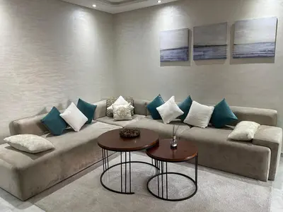 a living room with a couch with blue and white pillows at Miramare Cosy appartement pied dans l'eau avec piscine in Mohammedia