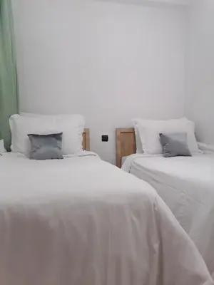 two beds in a room with white sheets and pillows at Appartement Fasthôtel Casablanca in Casablanca