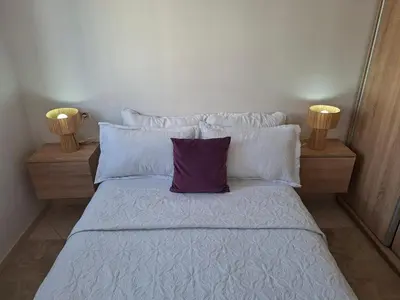 a bed with white sheets and a purple pillow at Appartement Fasthôtel Casablanca in Casablanca