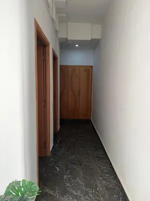 an empty hallway with wooden doors and a plant at Appt front la mer in Rabat