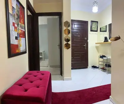 a living room with a red ottoman in front of a door at Appt Tranquile et Propre Cozy a petit prix in Casablanca
