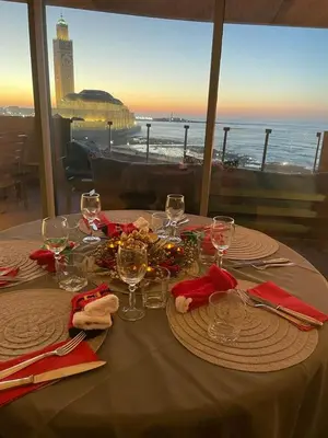 a table with plates and wine glasses and a view of the ocean at Marina Casa Del Mar - Amazing Sea & Mosque views in Casablanca