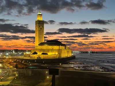 a large building with a clock tower at sunset at Marina Casa Del Mar - Amazing Sea & Mosque views in Casablanca