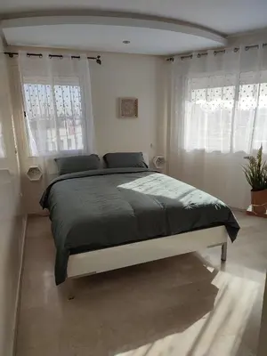 a bedroom with a large bed in a room with windows at Chaleureux Appartement à 1 min à pied de la Mosquée Hassan II in Casablanca