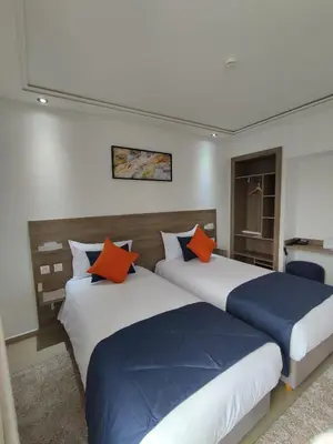 two beds with orange and blue pillows in a room at LOTUS HOTEL Casanearshore in Casablanca