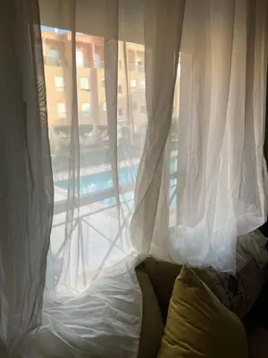 a window with white curtains and a couch in front at Ricoflores PALM in O Ben Slimane
