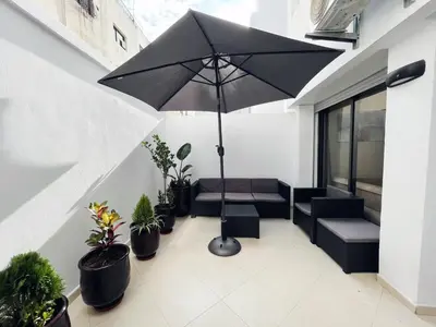a patio with an umbrella and chairs and potted plants at High Standing & cozy apartment in central Casablanca in Casablanca