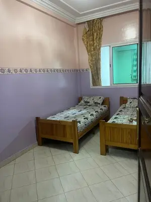 a bedroom with two beds and a mirror at Résidence Faouazi in Casablanca