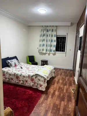 a bedroom with a bed and a chair and a window at Résidence Faouazi in Casablanca