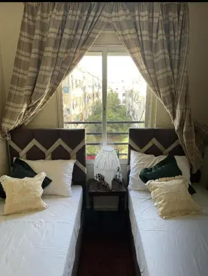 two beds in a room with a window at Appartement à peu près 10 mn de la plage et une demie heur verre le stade dhonneur in Casablanca
