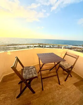 a table and two chairs on a balcony with the ocean at Apartement sur la corniche, vue sur mer in Rabat