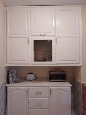 a white kitchen with white cabinets and a microwave at Bel appartement quartier Bourgogne in Casablanca