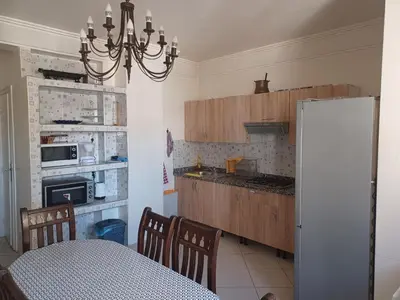a kitchen with a table and a refrigerator at Grand appartement lumineux avec balcon & parking idéal familles et pro in Casablanca
