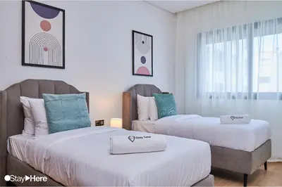 two beds in a room with white and blue at Stayhere Rabat - Hay Riad - Sophisticated Residence in Rabat