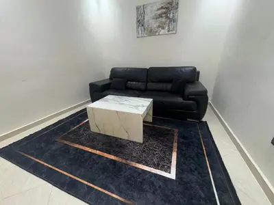 a living room with a black couch and a coffee table at magnifique appartement à rabat proche de la mer in Rabat