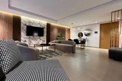 a living room with couches and a television on a wall at Casablanca Marina Ocean View - By AppartAli in Casablanca