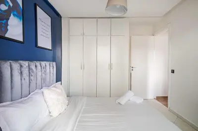 a bedroom with a white bed and a blue wall at TT Holidays-Rabat City Center in Rabat