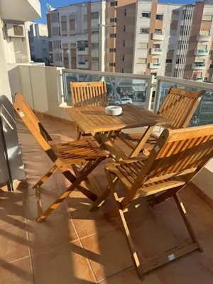 a wooden table and two chairs on a balcony at Coup de cœur a 5mn de l aéroport in Nouaceur