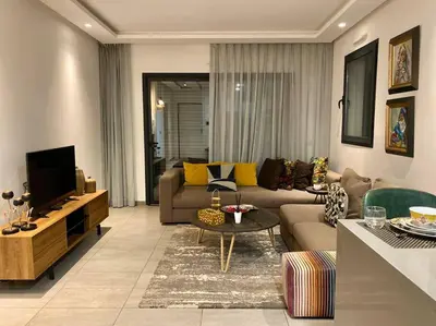 a living room with a couch and a tv at Faubourgs D Anfa Suite - By AppartAli in Casablanca