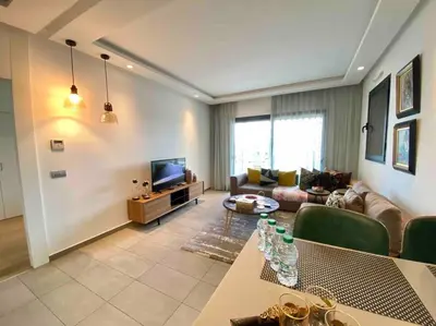 a living room with a couch and a tv at Faubourgs D Anfa Suite - By AppartAli in Casablanca