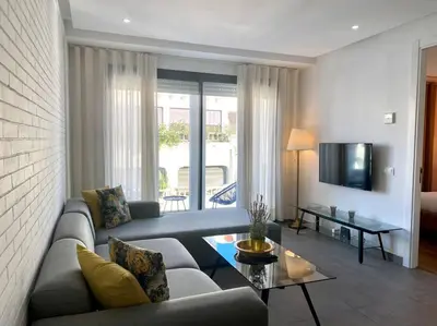 a living room with a couch and a table and a tv at Racine Zara Street - By AppartAli in Casablanca